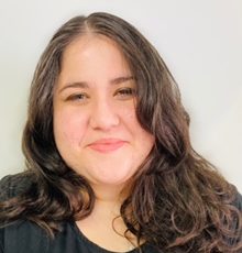 woman with open hair and in black color tshirt is smiling