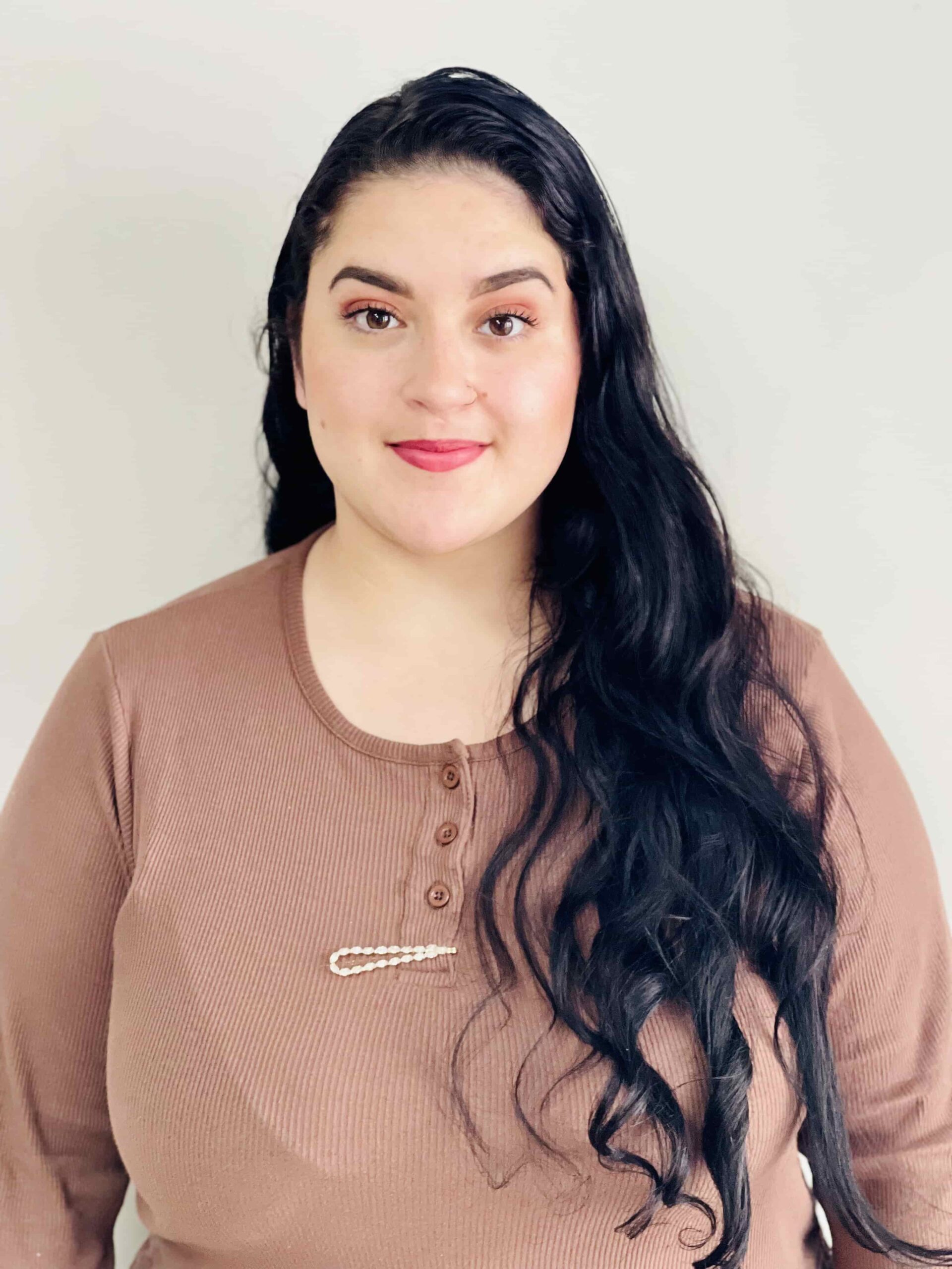 woman with open hair and skin color shirt is smiling